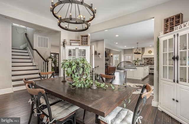 dining area with dark hardwood / wood-style flooring, a stone fireplace, and a notable chandelier