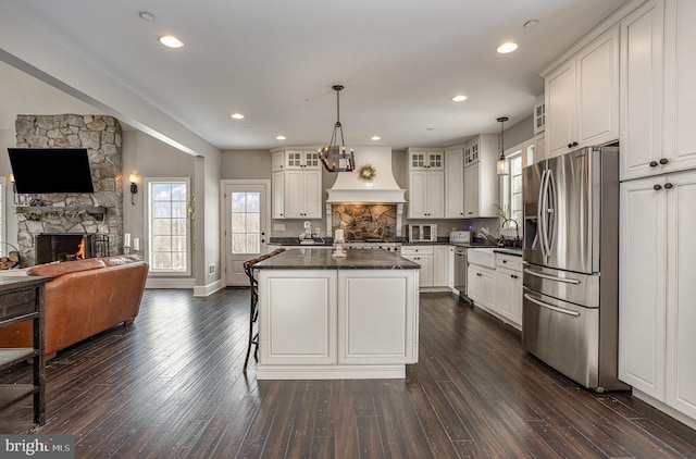 kitchen with pendant lighting, a fireplace, white cabinets, and stainless steel appliances