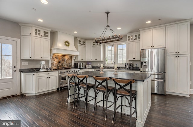 kitchen with white cabinets, appliances with stainless steel finishes, a center island, and custom exhaust hood