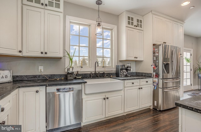 kitchen featuring stainless steel appliances, dark wood-type flooring, sink, white cabinetry, and hanging light fixtures