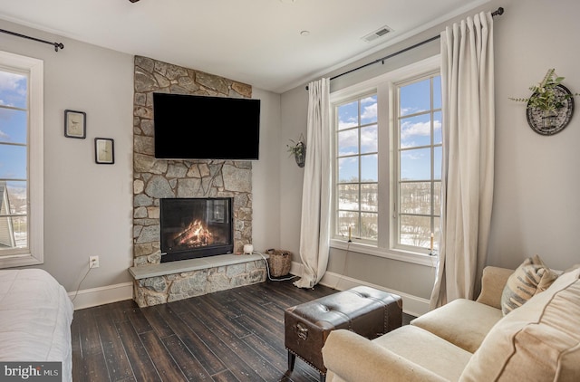 living room featuring plenty of natural light, dark hardwood / wood-style flooring, and a stone fireplace