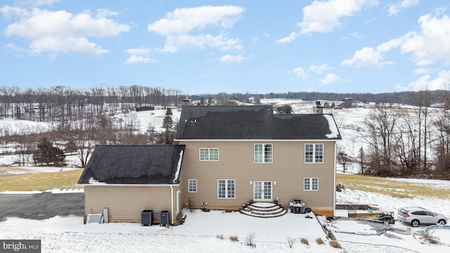 snow covered back of property featuring central AC unit