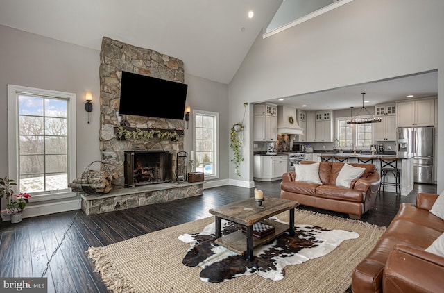 living room with dark wood-type flooring, high vaulted ceiling, and a stone fireplace