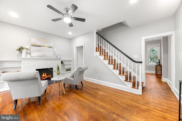 home office featuring ceiling fan, a stone fireplace, and hardwood / wood-style floors