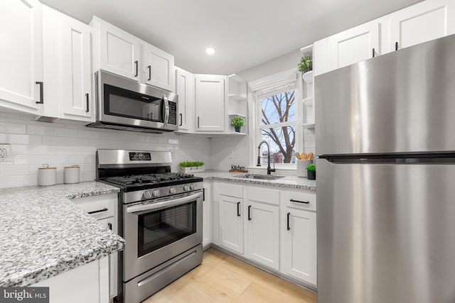 kitchen with light stone counters, stainless steel appliances, and white cabinetry