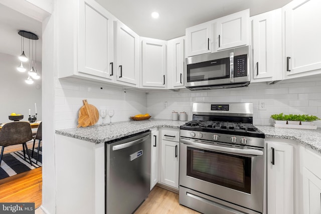 kitchen featuring light stone countertops, white cabinets, stainless steel appliances, decorative backsplash, and light wood-type flooring