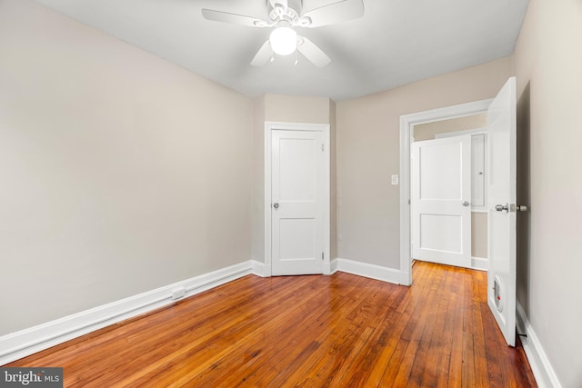 unfurnished bedroom with ceiling fan and dark wood-type flooring