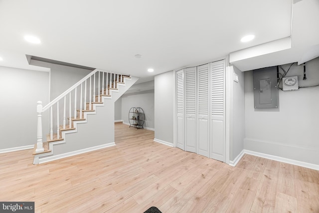 basement with electric panel and light hardwood / wood-style flooring