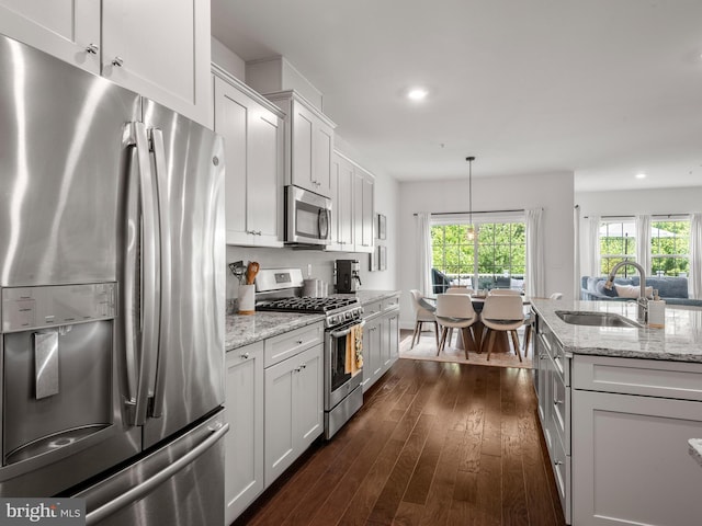 kitchen with appliances with stainless steel finishes, dark wood-type flooring, sink, decorative light fixtures, and white cabinets