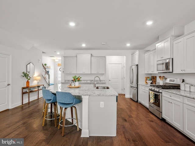 kitchen with white cabinetry, sink, appliances with stainless steel finishes, and an island with sink