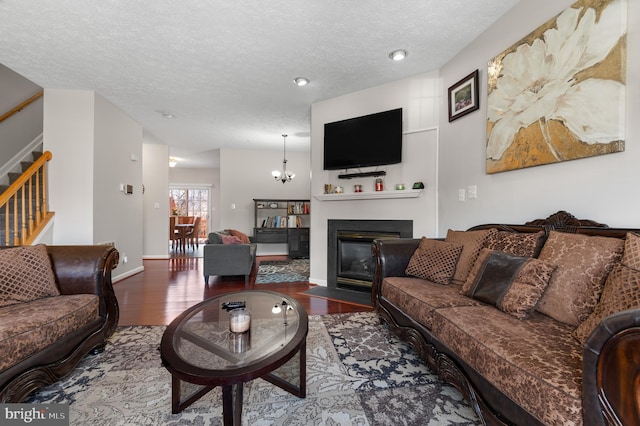 living room featuring stairway, a fireplace with flush hearth, wood finished floors, and a textured ceiling