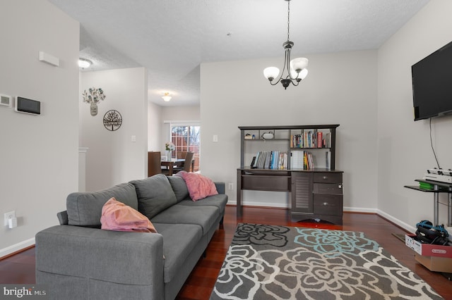 living room featuring a notable chandelier, wood finished floors, baseboards, and a textured ceiling