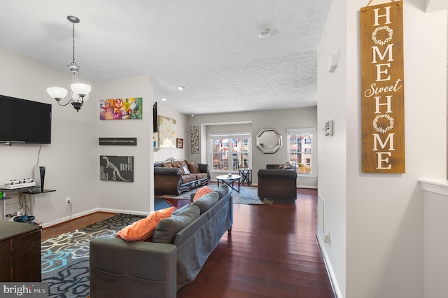 living area with baseboards, wood-type flooring, a textured ceiling, and an inviting chandelier