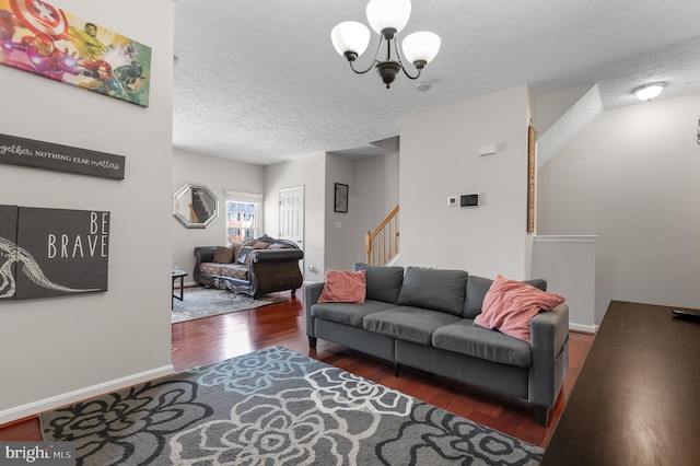 living room featuring a textured ceiling, wood finished floors, stairway, baseboards, and a chandelier