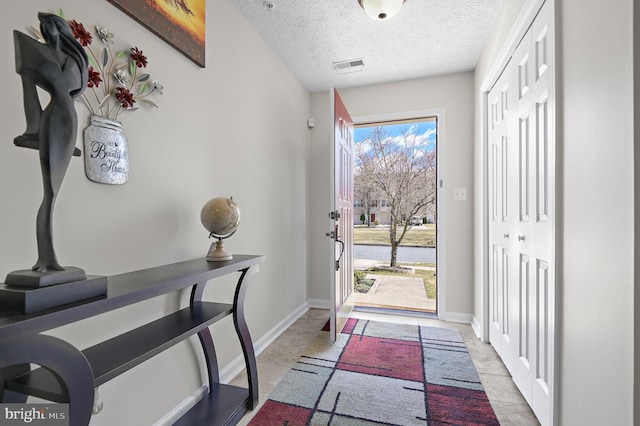 foyer with baseboards, visible vents, and a textured ceiling