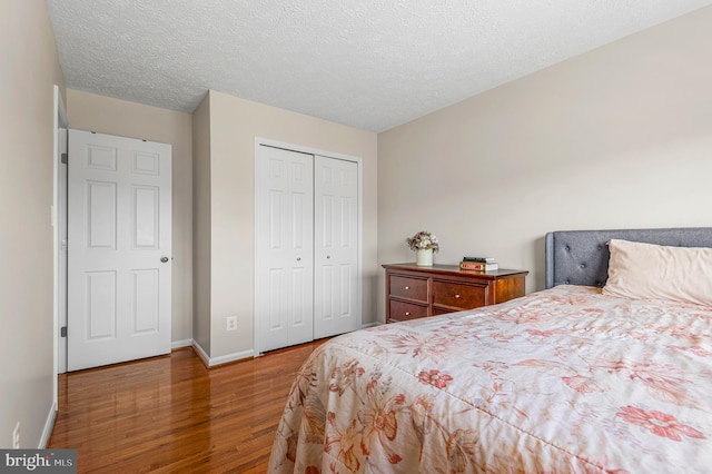 bedroom featuring baseboards, wood finished floors, a closet, and a textured ceiling