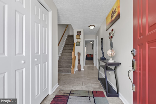 foyer with stairs, baseboards, and a textured ceiling