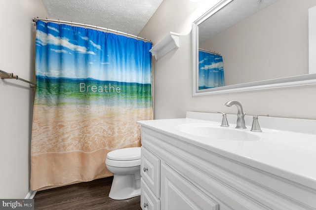 full bathroom with toilet, curtained shower, a textured ceiling, wood finished floors, and vanity