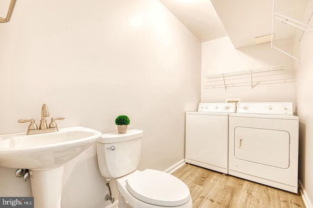 bathroom with baseboards, toilet, wood finished floors, and washer and clothes dryer