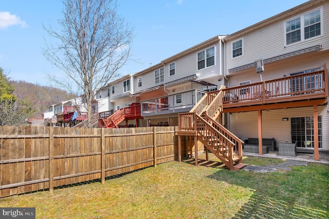 back of property featuring a lawn, a deck, fence, stairway, and a residential view