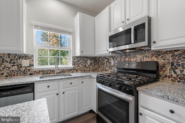 kitchen featuring a sink, white cabinets, backsplash, and stainless steel appliances