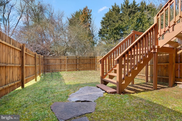 view of yard with a deck, stairway, and a fenced backyard