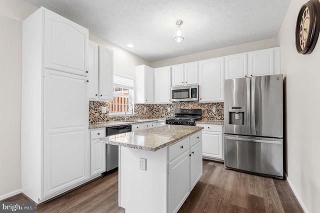 kitchen with backsplash, appliances with stainless steel finishes, light stone countertops, and dark wood-style flooring