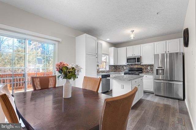 kitchen with backsplash, a center island, appliances with stainless steel finishes, wood finished floors, and white cabinetry