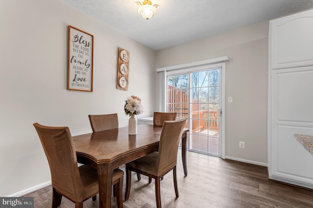 dining room with baseboards, light wood-style floors, and a textured ceiling