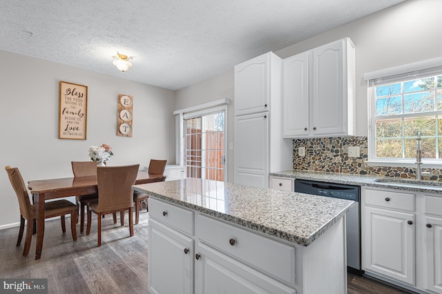 kitchen with a sink, plenty of natural light, dark wood-type flooring, and dishwasher