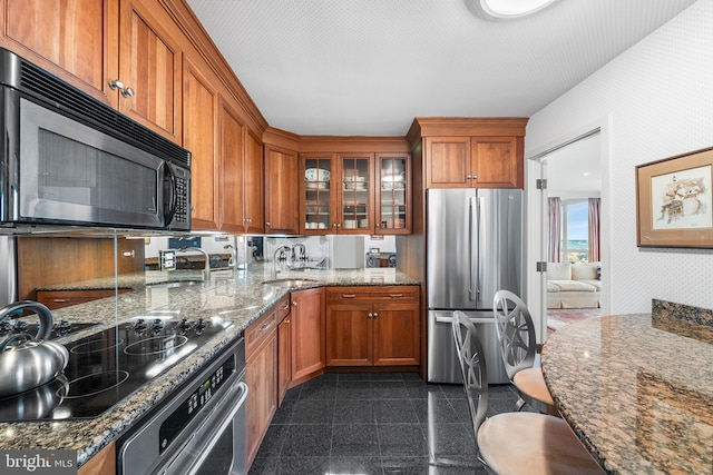 kitchen featuring stainless steel appliances, light stone countertops, and sink