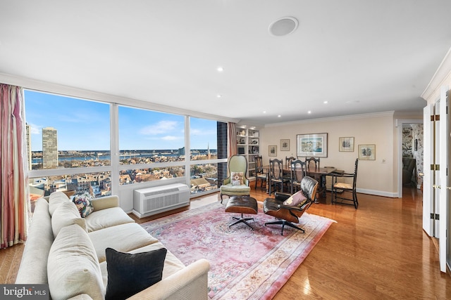 living room with floor to ceiling windows, a wall unit AC, ornamental molding, and wood-type flooring