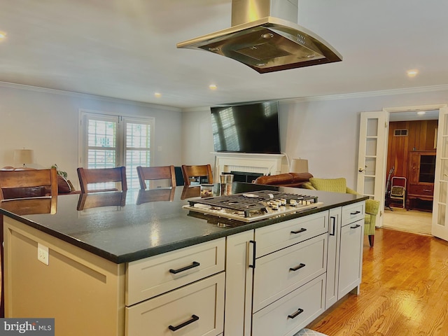 kitchen with stainless steel gas stovetop, island range hood, light hardwood / wood-style floors, and crown molding