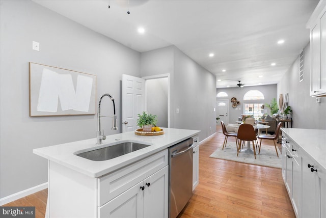 kitchen with ceiling fan, a kitchen island with sink, sink, dishwasher, and white cabinetry