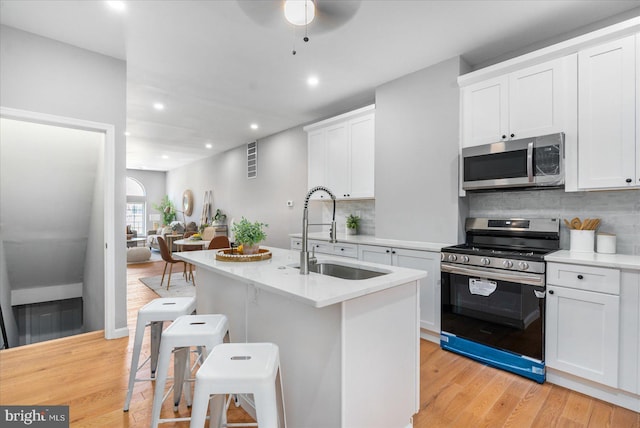 kitchen with white cabinetry, backsplash, a breakfast bar area, and range with gas cooktop