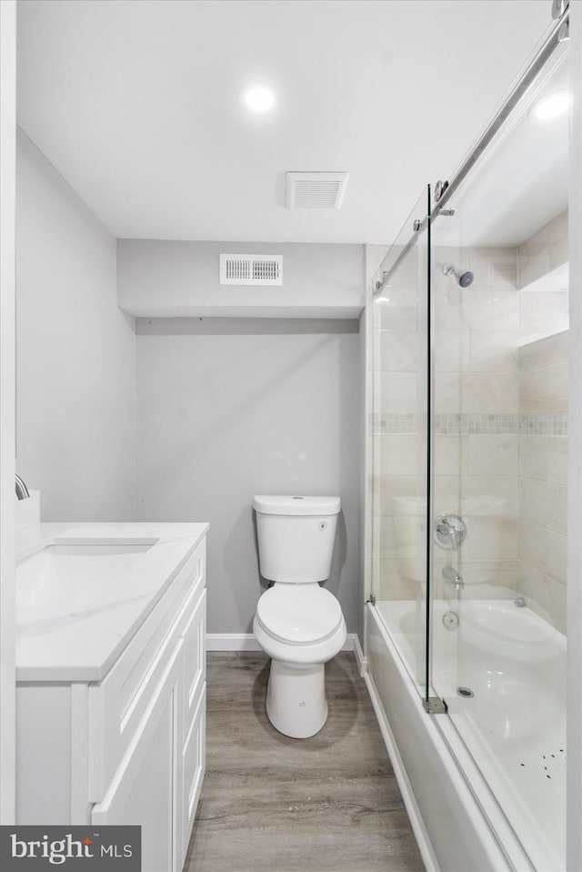 full bathroom featuring hardwood / wood-style flooring, vanity, toilet, and shower / bath combination with glass door