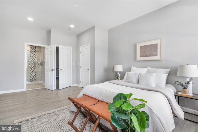 bedroom featuring connected bathroom and light hardwood / wood-style flooring