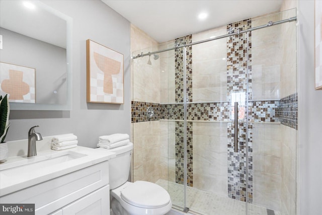 bathroom featuring vanity, toilet, and a shower with shower door