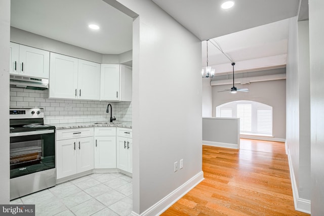 kitchen with stainless steel range with electric stovetop, backsplash, sink, ceiling fan, and white cabinetry