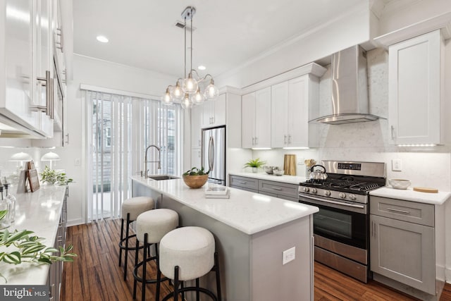 kitchen with sink, wall chimney exhaust hood, a center island with sink, and appliances with stainless steel finishes