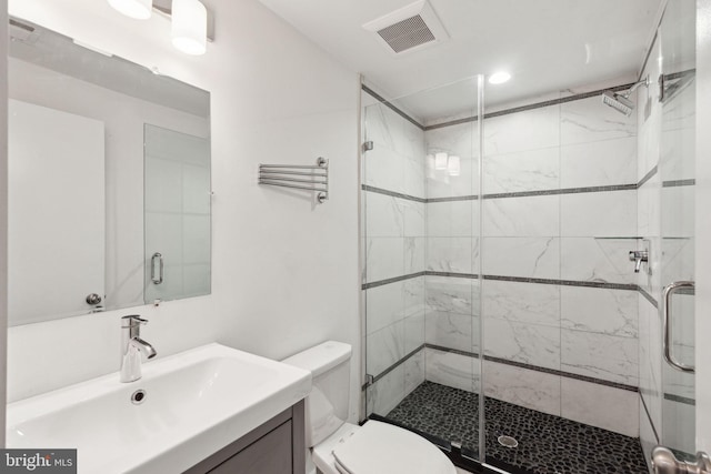 bathroom featuring vanity, toilet, and a shower with shower door