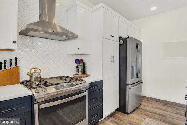 kitchen featuring white cabinets, wall chimney exhaust hood, and appliances with stainless steel finishes