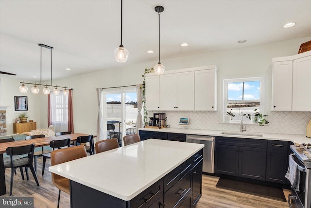 kitchen with a healthy amount of sunlight, a sink, light countertops, appliances with stainless steel finishes, and backsplash