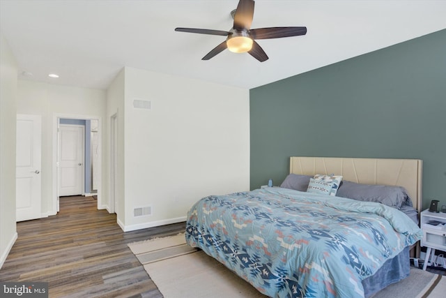 bedroom with visible vents, baseboards, wood finished floors, and a ceiling fan