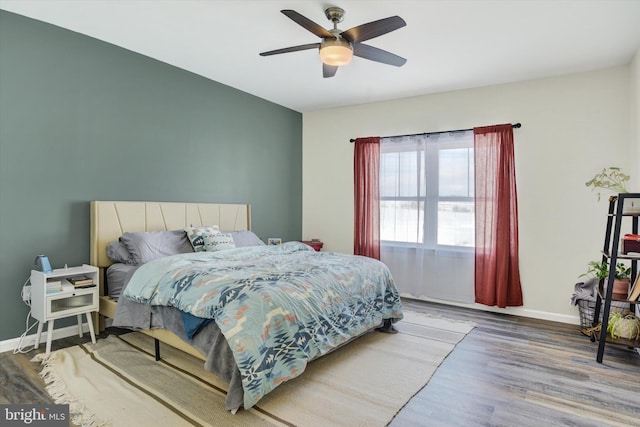 bedroom featuring wood finished floors, baseboards, and ceiling fan