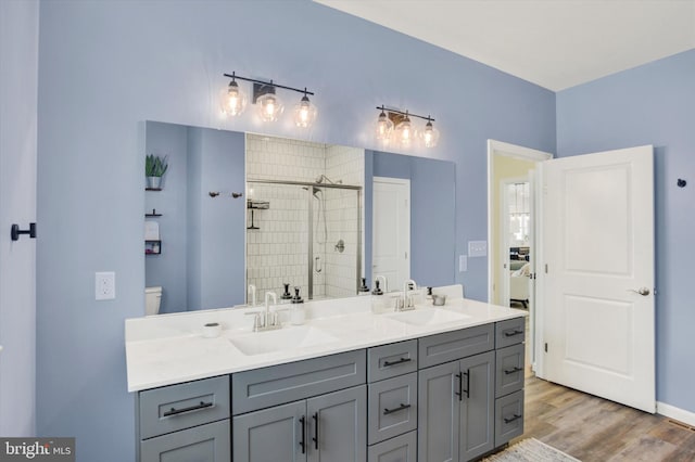 full bathroom with double vanity, wood finished floors, a stall shower, and a sink