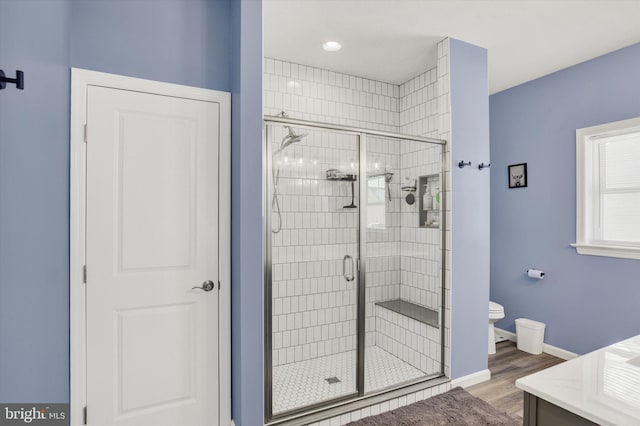 full bath with baseboards, wood finished floors, toilet, and a stall shower