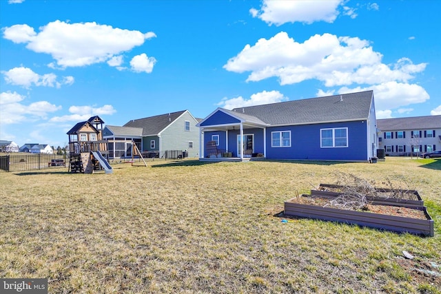 rear view of house with a garden, a yard, central AC, and a playground