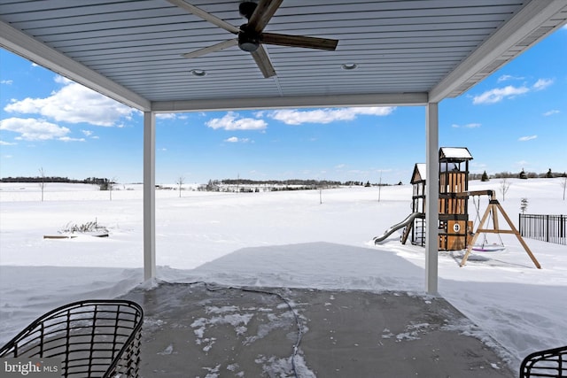 snow covered patio featuring ceiling fan and a playground