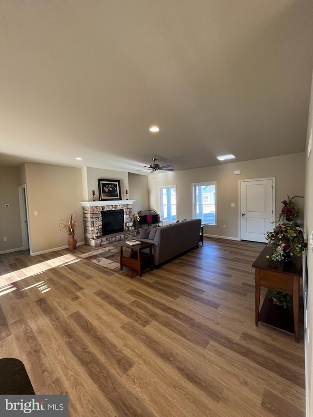 living room with ceiling fan, a fireplace, and wood-type flooring